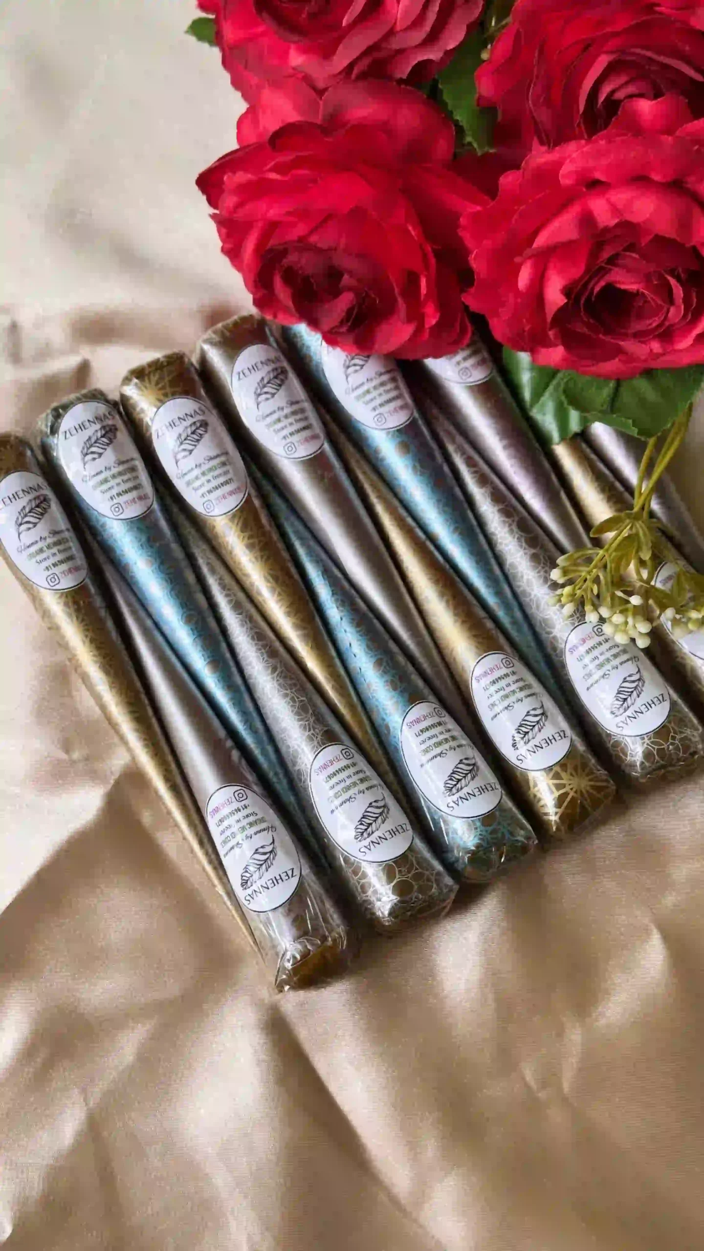 henna cone with brand name sticker on it with ared rose and white satin cloth