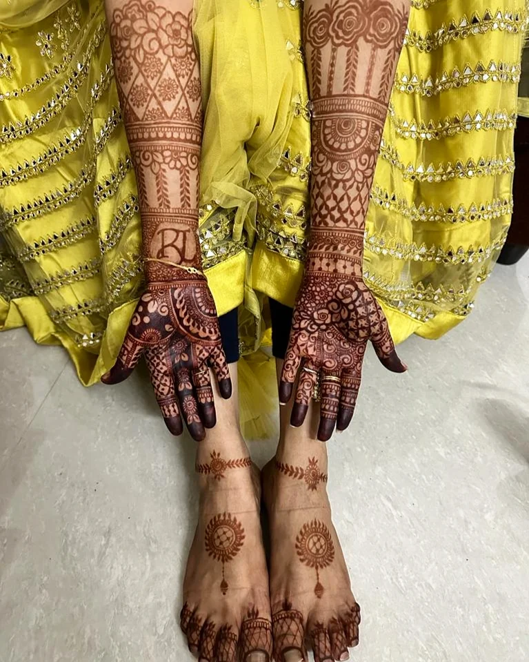a girl showing her hand and feet stained mehendi