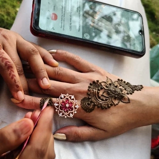 applying henna with a white background desk having phone by side